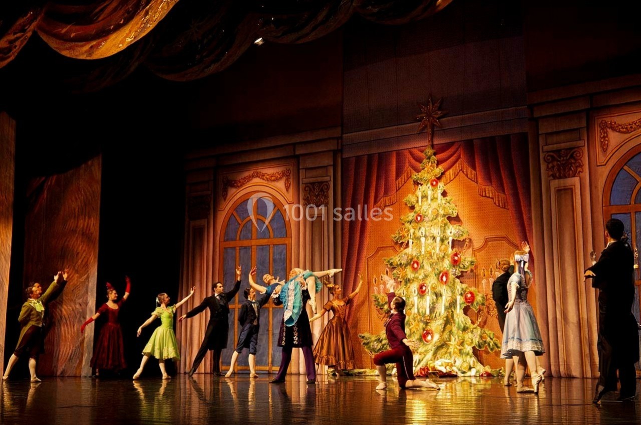 Location salle Dammarie-les-Lys (Seine-et-Marne) - Espace Pierre Bachelet #13 Des danseurs en costume exécutent une scène de ballet devant un grand sapin de Noël décoré sur une scène de théâtre.