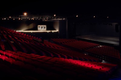 Entrée vitrée illuminée avec des plantes en pot disposées en rangées et éclairage coloré.