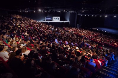 Entrée vitrée illuminée avec des plantes en pot disposées en rangées et éclairage coloré.