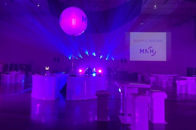 Entrée vitrée illuminée avec des plantes en pot disposées en rangées et éclairage coloré.