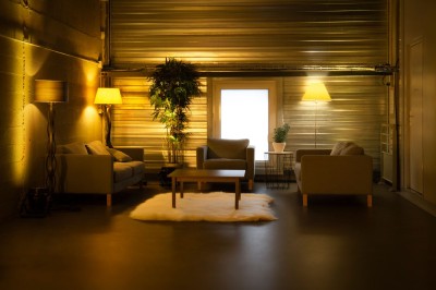 Entrée vitrée illuminée avec des plantes en pot disposées en rangées et éclairage coloré.