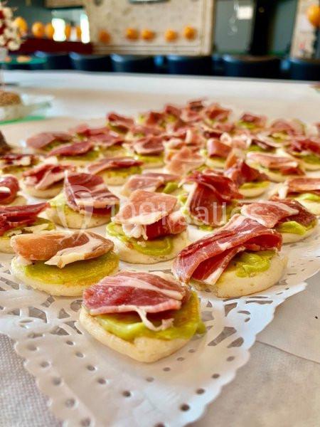 Plateau de canapés garnis de crème d'avocat et de tranches de jambon disposés sur une table.