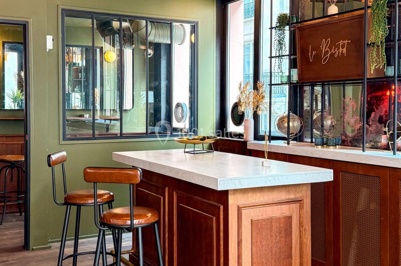 Comptoir en bois avec plateau en marbre, tabourets hauts et décorations végétales dans un intérieur au design moderne.