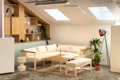 Salon chaleureux avec canapé jaune, fauteuils en rotin, table basse ronde, lampes et décorations murales abstraites.