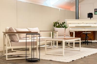 Salon chaleureux avec canapé jaune, fauteuils en rotin, table basse ronde, lampes et décorations murales abstraites.