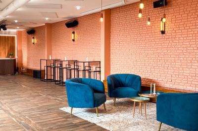 Salon chaleureux avec canapé jaune, fauteuils en rotin, table basse ronde, lampes et décorations murales abstraites.