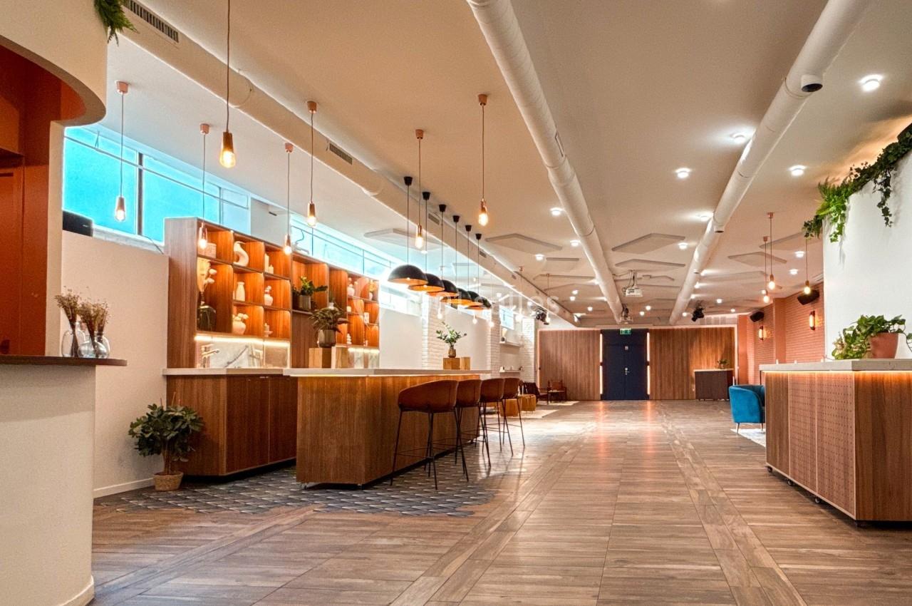 Espace intérieur moderne avec parquet, comptoirs en bois, éclairage suspendu et plantes décoratives.