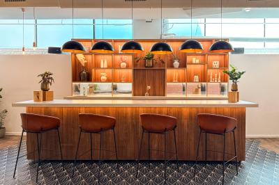 Salon chaleureux avec canapé jaune, fauteuils en rotin, table basse ronde, lampes et décorations murales abstraites.