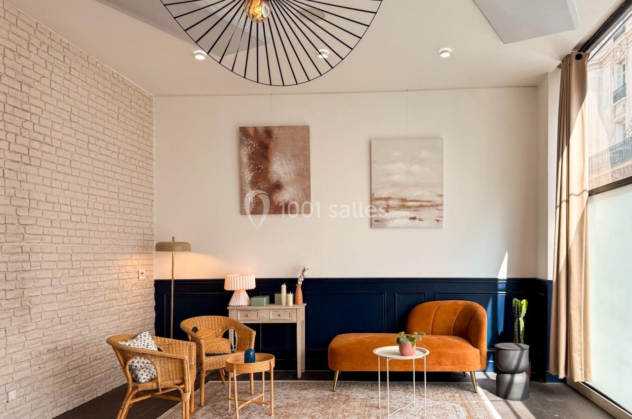 Salon lumineux avec murs en briques et bleu marine, mobilier en rotin et velours, et décoration minimaliste.