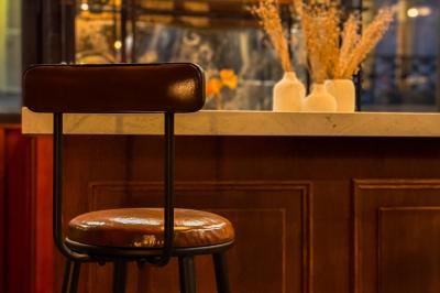 Salon chaleureux avec canapé jaune, fauteuils en rotin, table basse ronde, lampes et décorations murales abstraites.