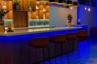 Salon chaleureux avec canapé jaune, fauteuils en rotin, table basse ronde, lampes et décorations murales abstraites.