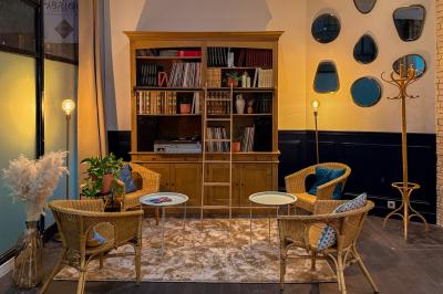 Salon chaleureux avec canapé jaune, fauteuils en rotin, table basse ronde, lampes et décorations murales abstraites.