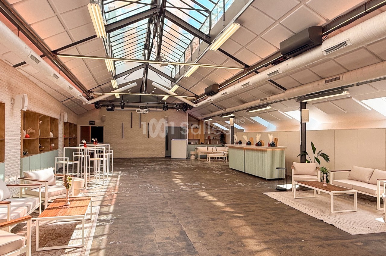 Espace lumineux avec verrière, mobilier moderne et coin salon, dans un intérieur de style industriel.