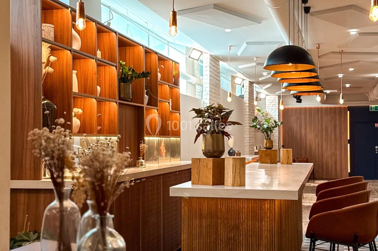 Espace intérieur moderne avec comptoirs en bois, étagères éclairées, suspensions design et chaises hautes.