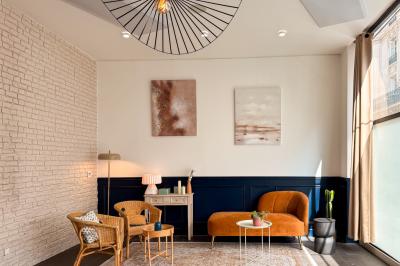 Salon cosy avec canapé jaune, fauteuils en rotin, table basse ronde, lampes et décorations murales dans une ambiance…