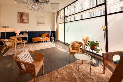 Salon cosy avec canapé jaune, fauteuils en rotin, table basse ronde, lampes et décorations murales dans une ambiance…