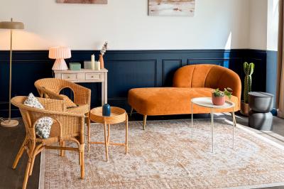 Salon cosy avec canapé jaune, fauteuils en rotin, table basse ronde, lampes et décorations murales dans une ambiance…