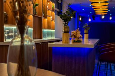 Salon cosy avec canapé jaune, fauteuils en rotin, table basse ronde, lampes et décorations murales dans une ambiance…