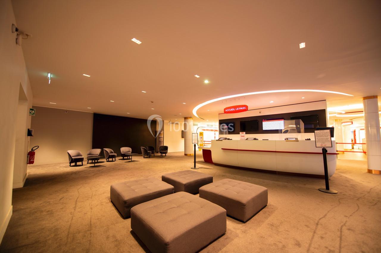 Espace d'accueil moderne avec comptoir blanc, sièges rembourrés et éclairage chaleureux.