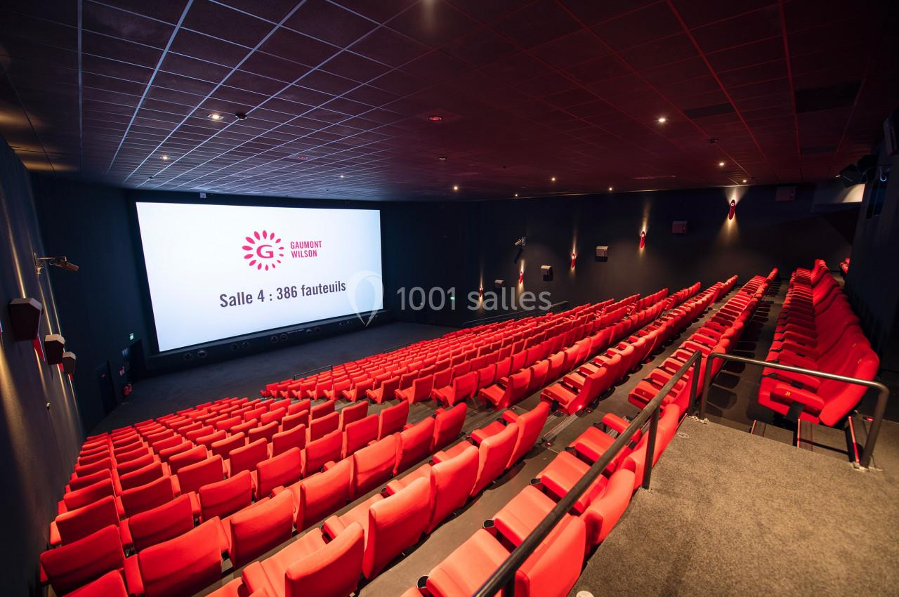 Salle de cinéma moderne avec rangées de fauteuils rouges et grand écran affichant ’Salle 4 : 386 fauteuils’.