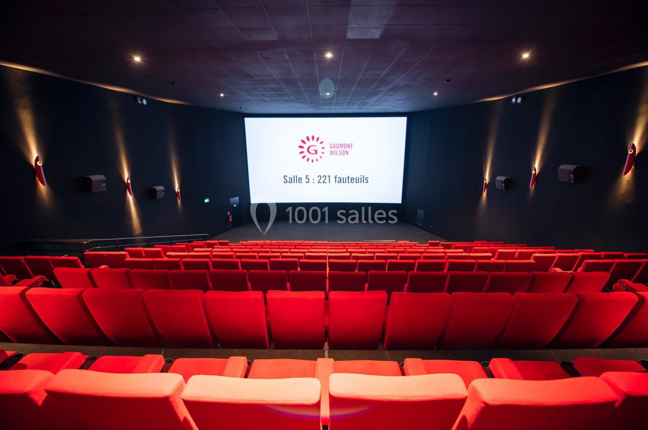 Salle de cinéma vide avec des rangées de fauteuils rouges et un écran affichant ’Salle 5 : 221 fauteuils’.