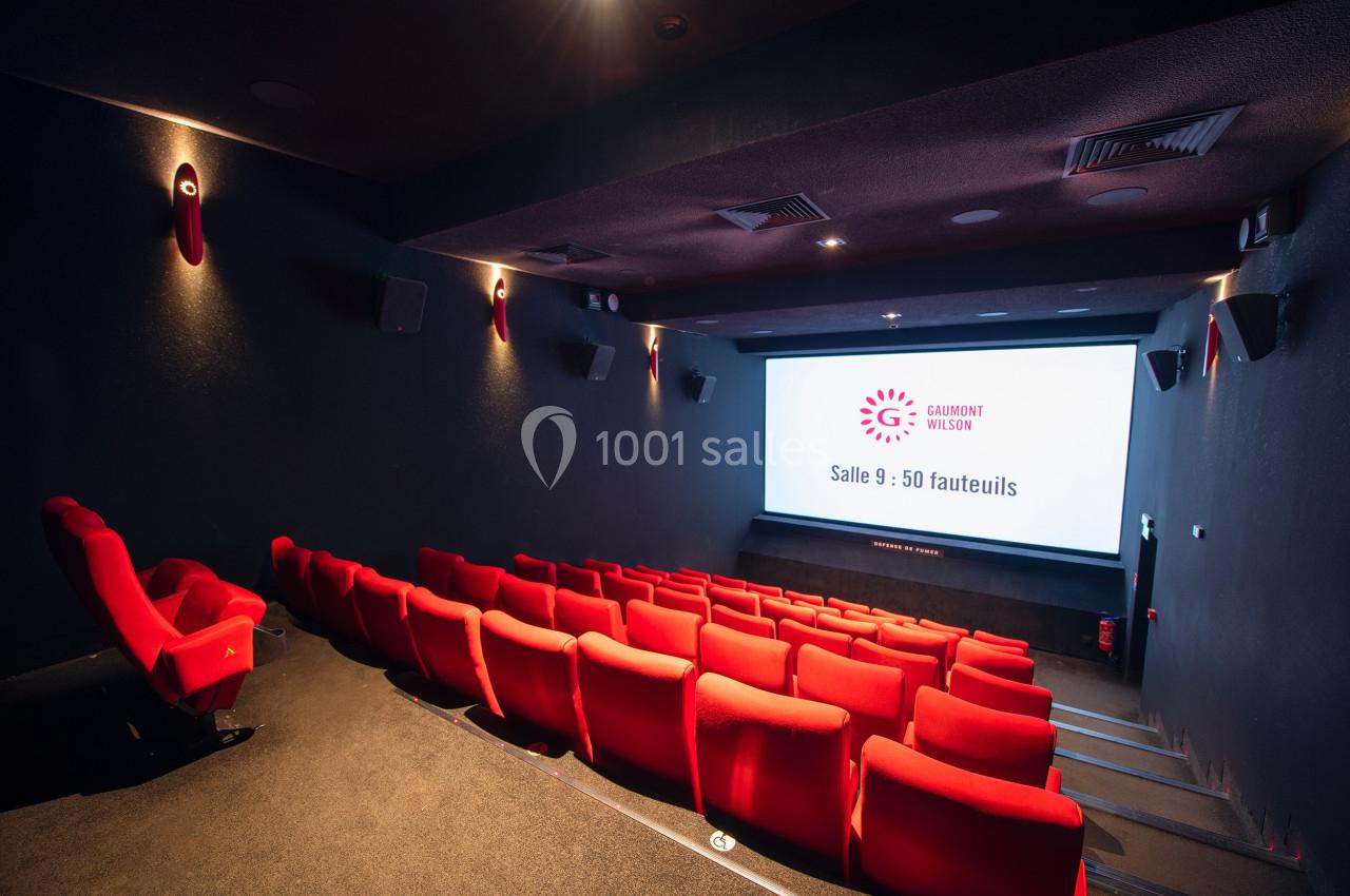 Salle de cinéma vide avec rangées de fauteuils rouges et écran affichant ’Salle 9 : 50 fauteuils’.