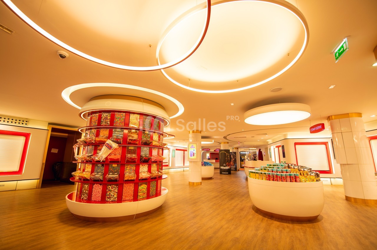 Intérieur d'un magasin lumineux avec des étagères circulaires remplies de bonbons et un sol en bois clair.