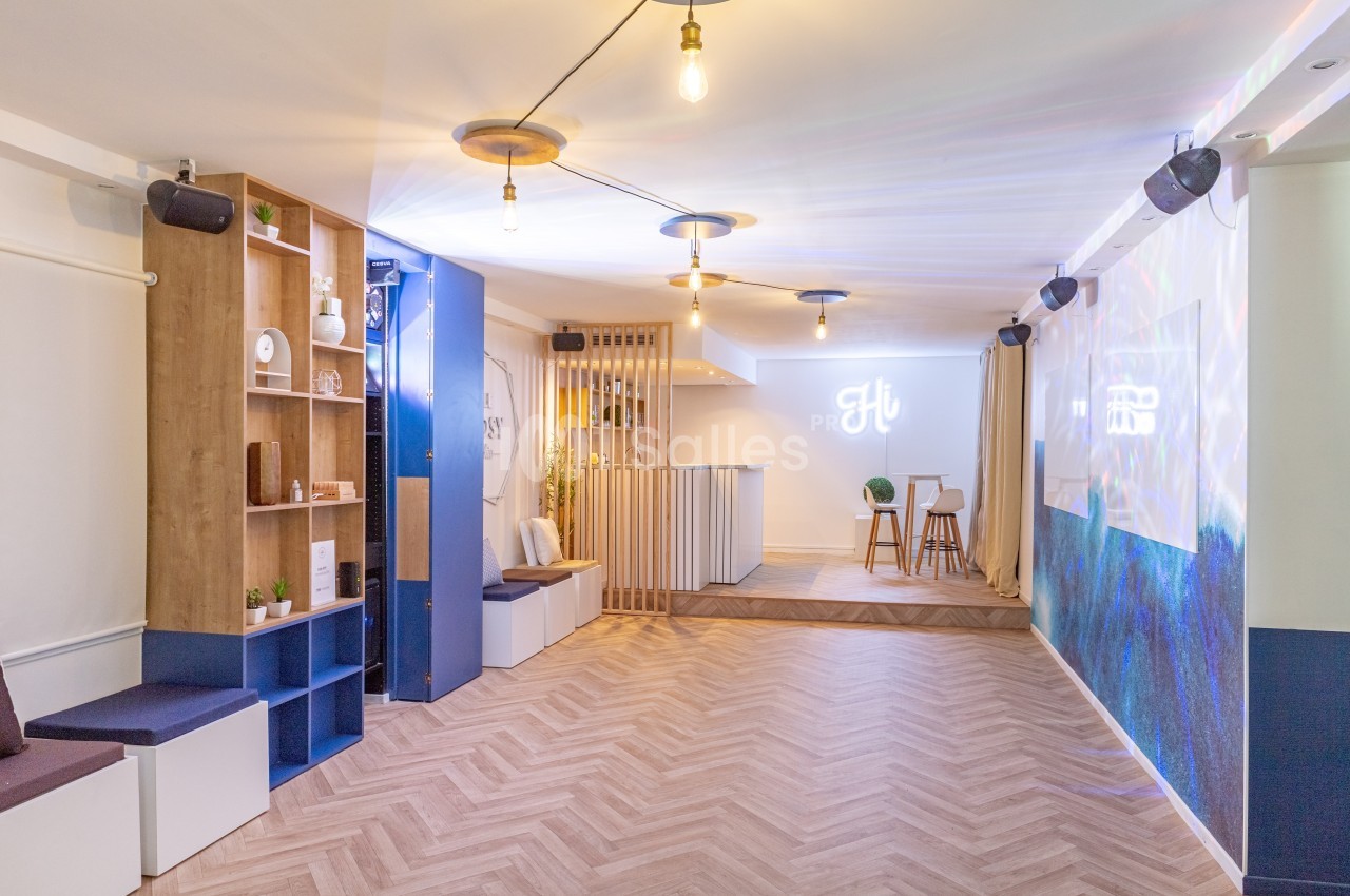 Salle lumineuse avec parquet, espace bar, étagères en bois, banquettes et décorations modernes.
