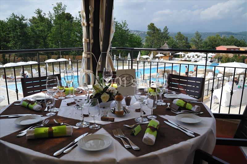 Table dressée avec élégance sur une terrasse surplombant une piscine et un paysage verdoyant.