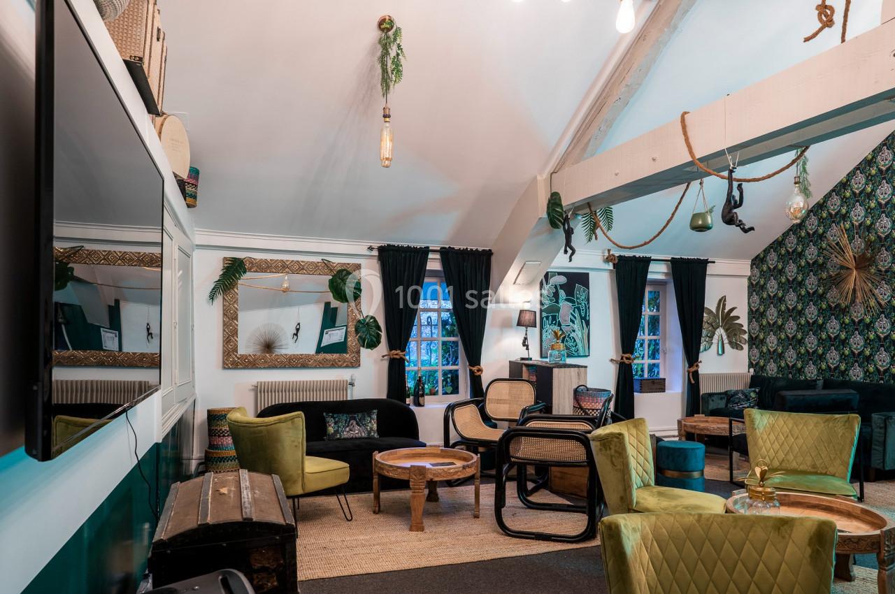 Salon chaleureux avec fauteuils colorés, tables en bois, miroirs encadrés et décoration végétale sur les murs.