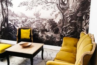 Deux lits simples avec tête de lit noire, coussins jaunes, et tableaux d'animaux anthropomorphes au mur.