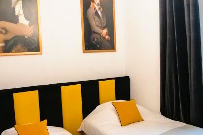 Deux lits simples avec tête de lit noire, coussins jaunes, et tableaux d'animaux anthropomorphes au mur.