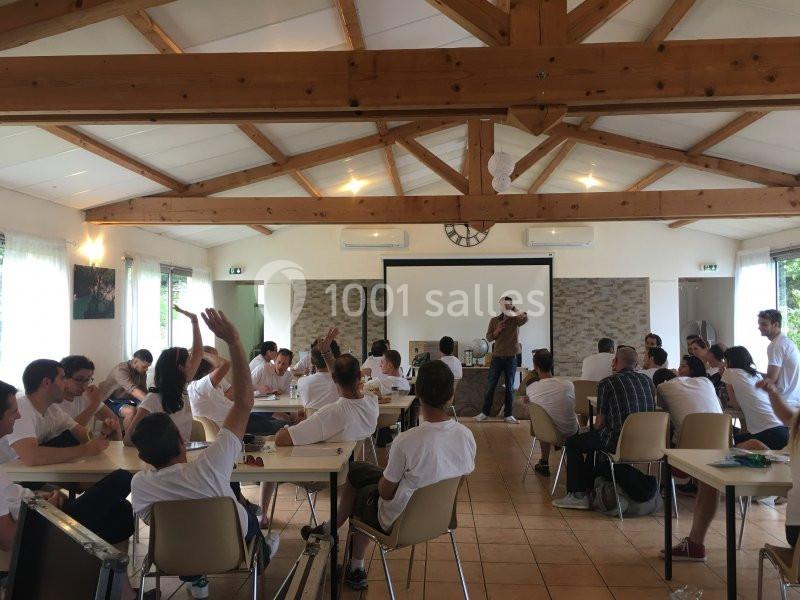 Un groupe de personnes participe à une formation ou réunion dans une salle lumineuse avec poutres apparentes.