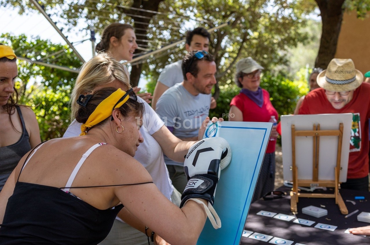 Des personnes participent à une activité de peinture en plein air, dont une femme portant un gant de boxe.