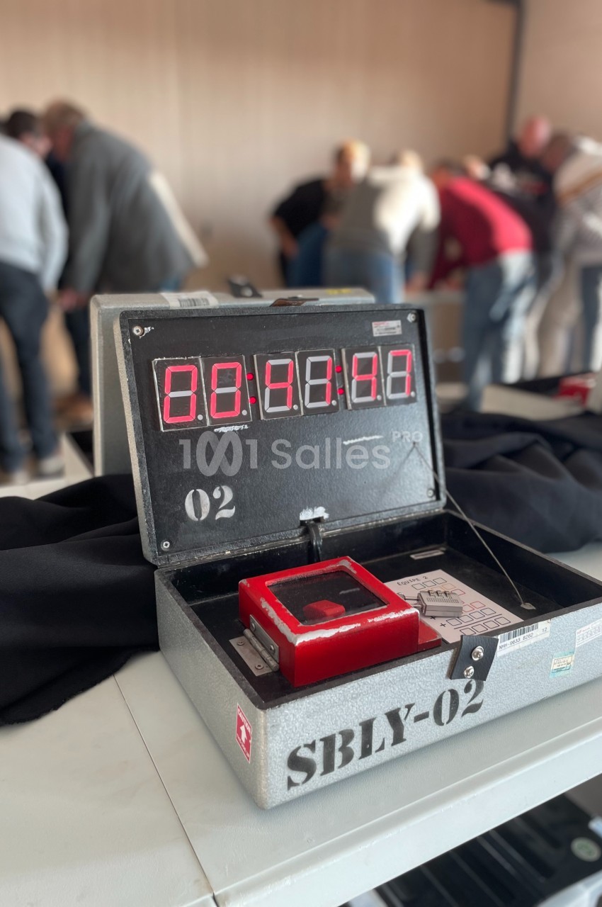 Boîtier métallique ouvert avec un chronomètre numérique affichant 00:40:00, entouré de personnes en arrière-plan.