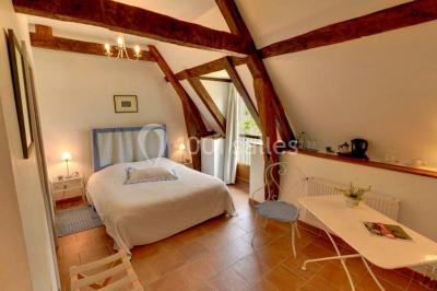 Miniature Location salle Amécourt (Eure) - Domaine du Patis #11 Chambre lumineuse avec poutres apparentes, lit double, table blanche, et vue sur un balcon avec verdure.