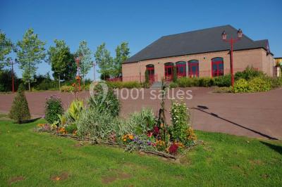 Salle de réunion vide avec tables disposées en U, chaises en bois, murs en briques et grandes fenêtres laissant entrer la…