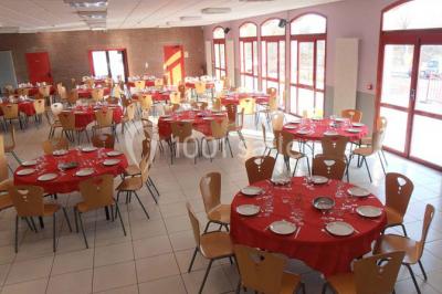 Salle de réunion vide avec tables disposées en U, chaises en bois, murs en briques et grandes fenêtres laissant entrer la…