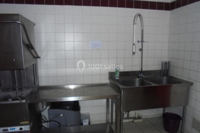 Salle de réunion vide avec tables disposées en U, chaises en bois, murs en briques et grandes fenêtres laissant entrer la…