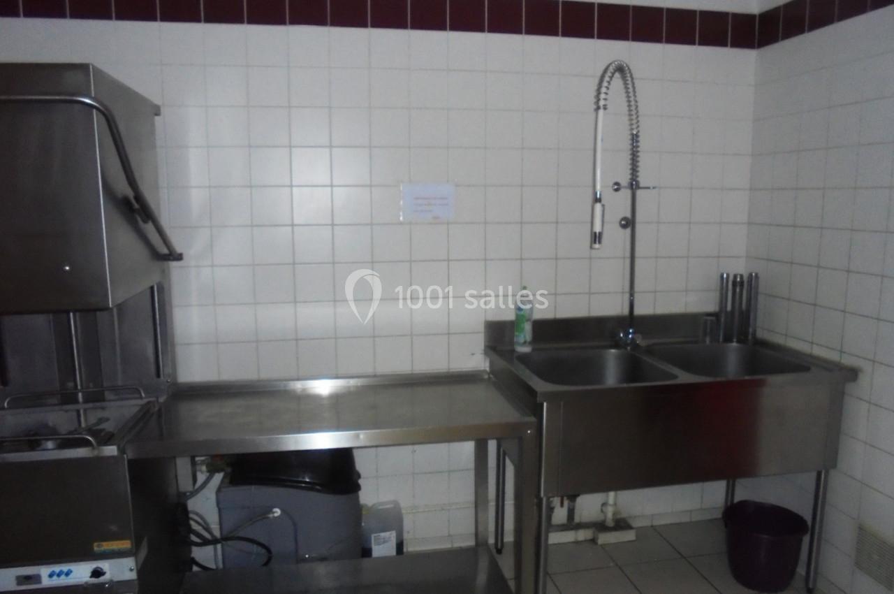 Évier double en acier inoxydable avec robinet flexible, adjacent à un lave-vaisselle dans une cuisine carrelée.