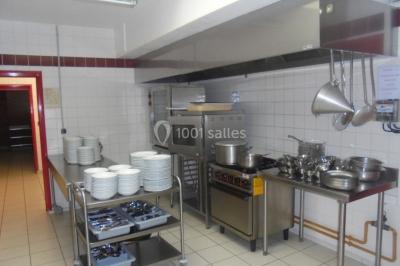 Salle de réunion vide avec tables disposées en U, chaises en bois, murs en briques et grandes fenêtres laissant entrer la…