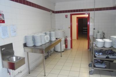 Salle de réunion vide avec tables disposées en U, chaises en bois, murs en briques et grandes fenêtres laissant entrer la…