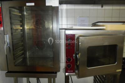 Salle de réunion vide avec tables disposées en U, chaises en bois, murs en briques et grandes fenêtres laissant entrer la…