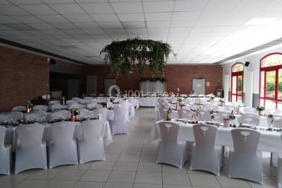 Salle de réunion vide avec tables disposées en U, chaises en bois, murs en briques et grandes fenêtres laissant entrer la…