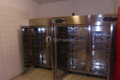 Salle de réunion vide avec tables disposées en U, chaises en bois, murs en briques et grandes fenêtres laissant entrer la…