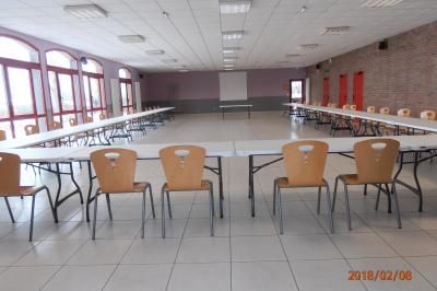 Salle de réunion vide avec tables disposées en U, chaises en bois, murs en briques et grandes fenêtres laissant entrer la…