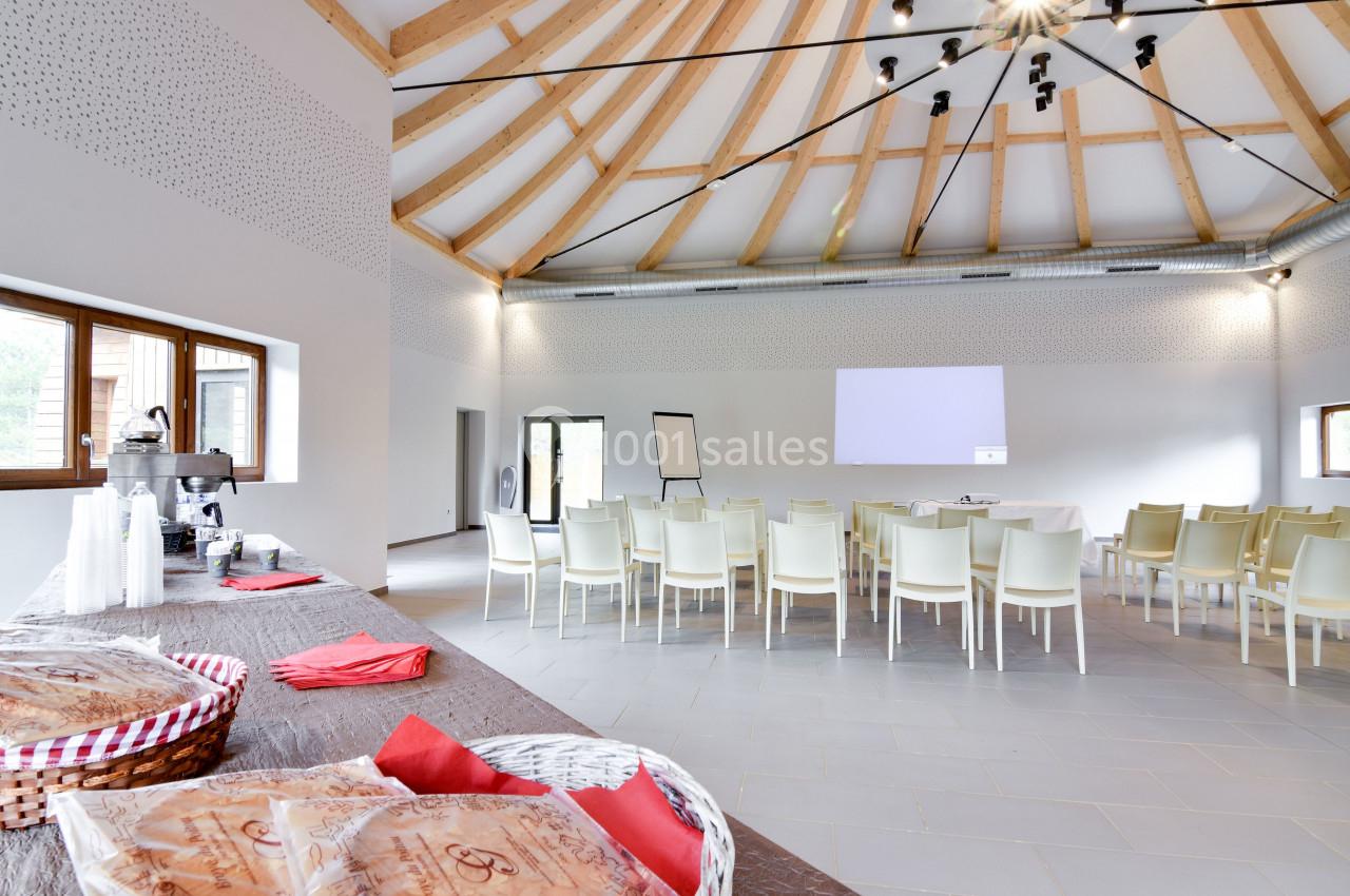 Salle lumineuse avec des chaises disposées face à un écran de projection, table avec collations au premier plan.