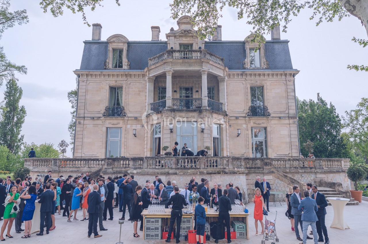 Groupe de personnes rassemblées devant un château en pierre lors d'un événement en plein air.