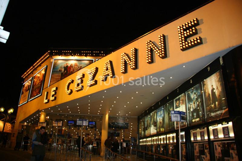 Façade illuminée du cinéma Le Cézanne avec affiches de films et entrée vitrée en soirée.