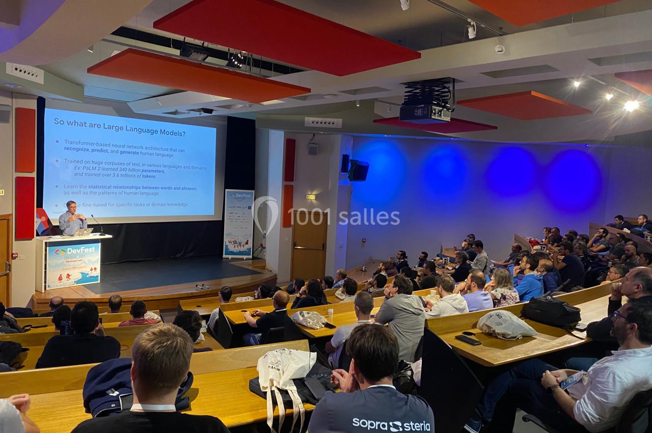 Un conférencier présente un sujet sur les modèles de langage devant un public attentif dans un amphithéâtre.